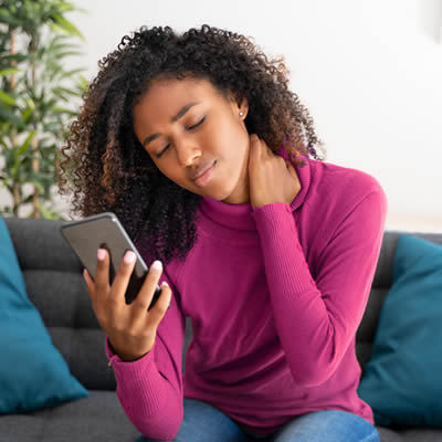 teen with neck pain holding phone