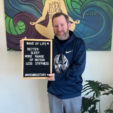 Man wearing blue hoodie holding a sign