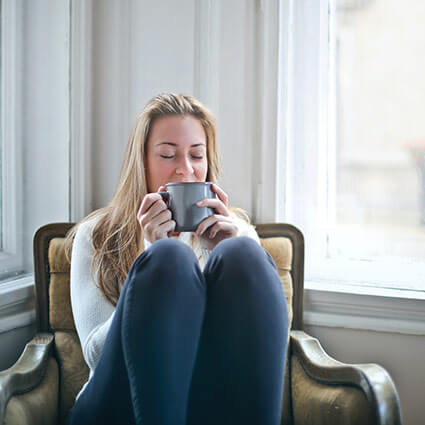 person sitting in chair enjoying cup of tea