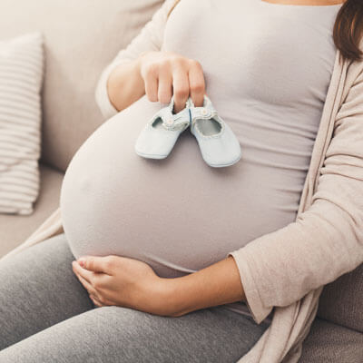 pregnant mom holding baby shoes on belly