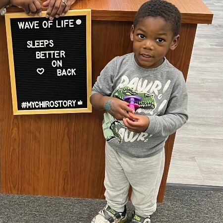 Young boy standing by a sign