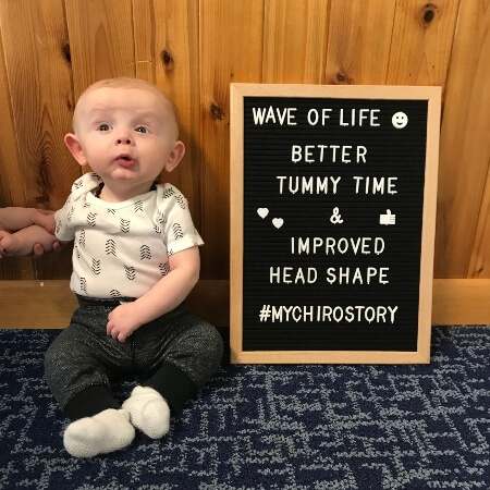 Baby sitting next to a sign