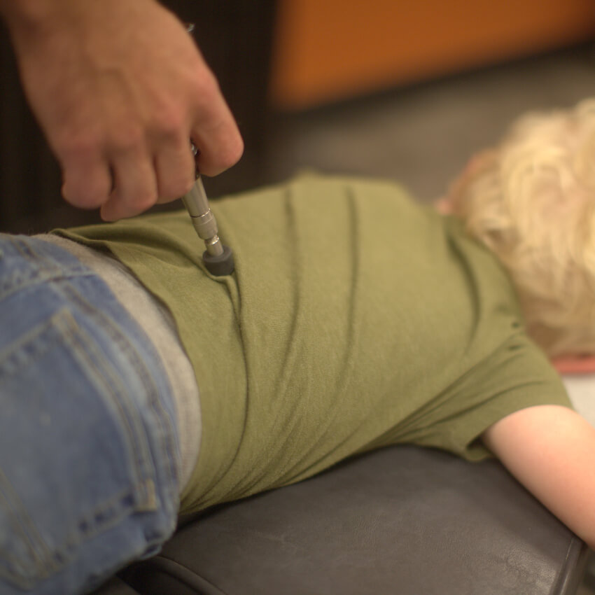 Chiropractic FIRST patient having back adjusted with tool
