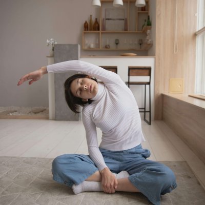 Woman performing a side stretch yoga pose indoors, emphasizing relaxation and fitness in a cozy setting.