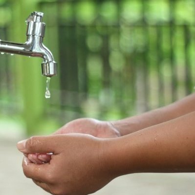 kid washing hands in open faucet