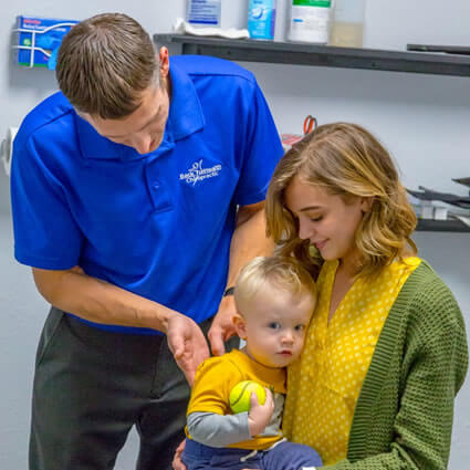 Dr. Carroll adjusting boy on moms lap