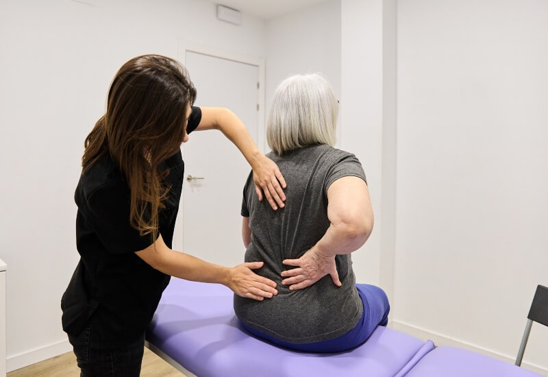 A physical therapist gives a back massage to a woman, focusing on chiropractic care for disc herniations in Boston, MA.