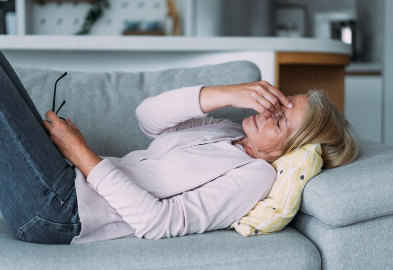 A woman laying on her sofa suffering from Fatigue in Boston