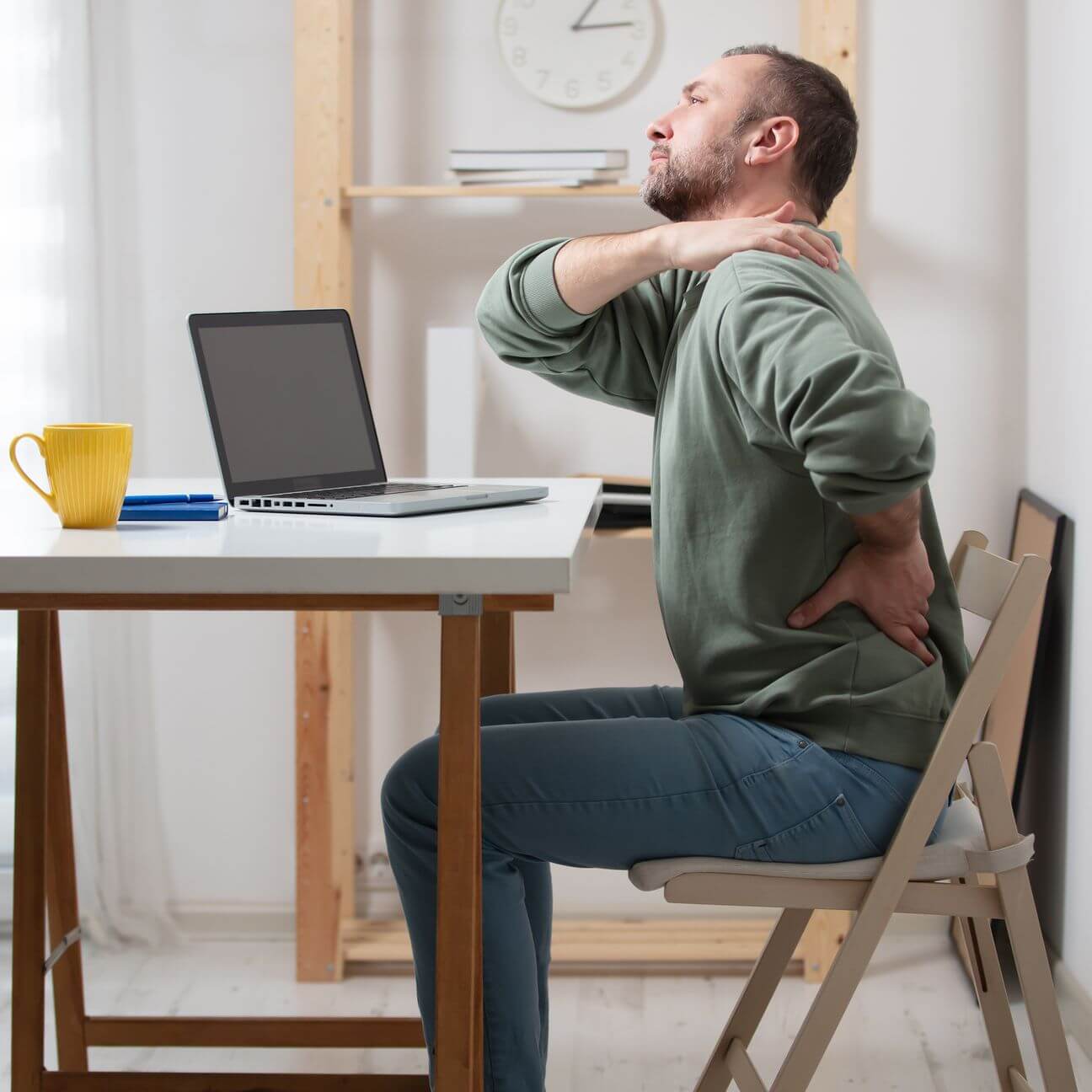 A man at a desk in Boston, MA, is dealing with back pain and sciatica while seated