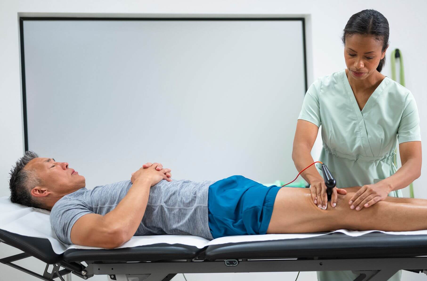 A man receives an electric massage on his leg at Sports Chiropractic in Boston, MA