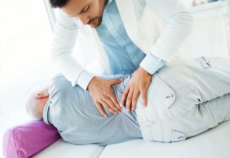 A doctor gives a back massage to a man in a chiropractic clinic in Boston, MA.