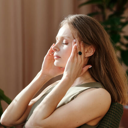 woman sitting down with her hands on her temples