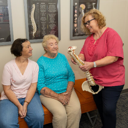doctor talking to patients holding spine model