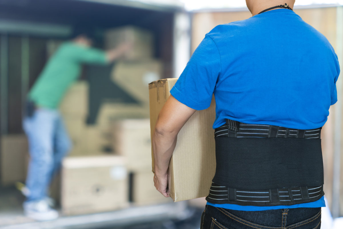 Man lift heavy carton wearing support belt for protect back