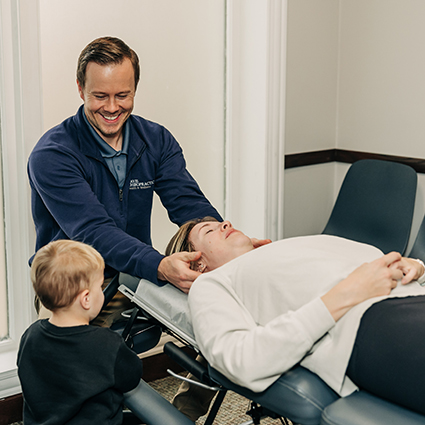 Grand Rapids Chiropractor Dr John smiling while doing neck adjustment