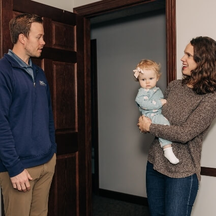 Dr John talking with a patient holding their baby