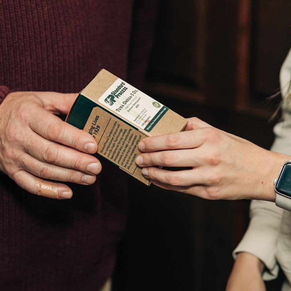 Patient and staff member reviewing a box of Standard Process Tuna Omega-3 Oil