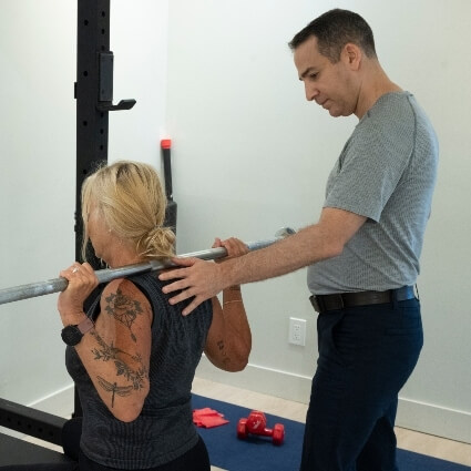 Downtown Toronto chiropractor Dr Michael assisting patient using barbell