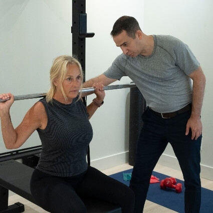 Downtown Toronto chiropractor Dr Michael guiding patient using barbell