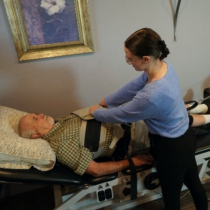 Staff helping patient on spinal decompression table