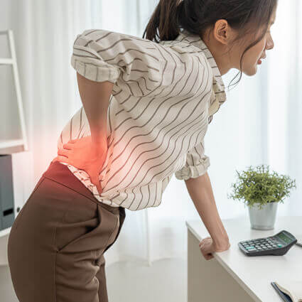 business-woman-leaning-on-desk-with-back-pain-sq