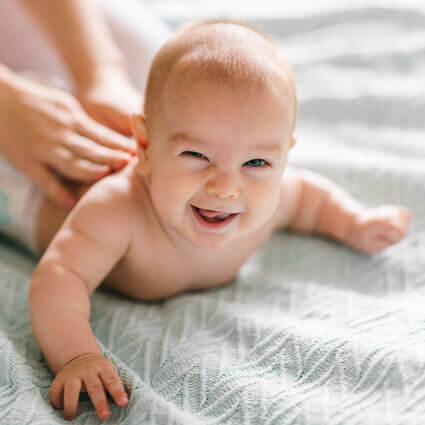 infant looking up laughing while lying on tummy