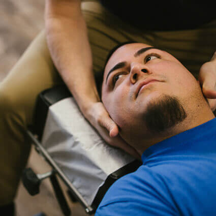 man in blue shirt laying on table having neck adjustment