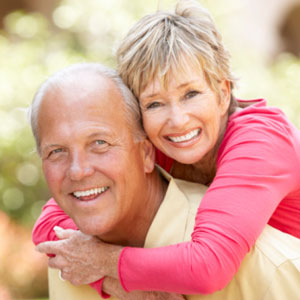 Older couple smiling and hugging outdoors.