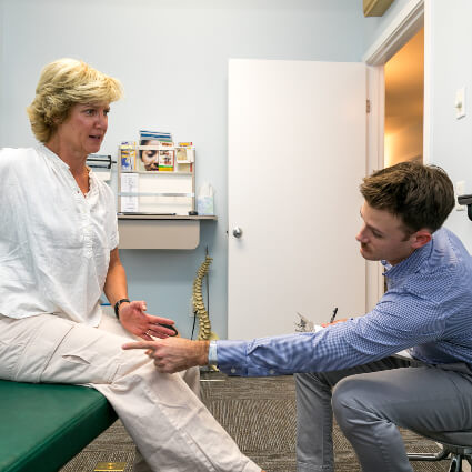 Dr. Mitchell touching woman's knee on adjusting table