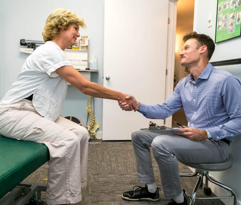 Harvard Chiropractor Dr. Mitchell shaking hands with female patient