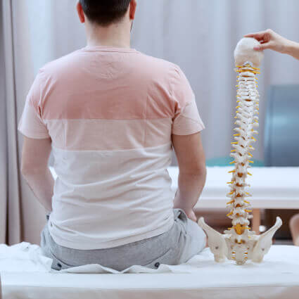 man-sitting-next-to-spine-model-sq