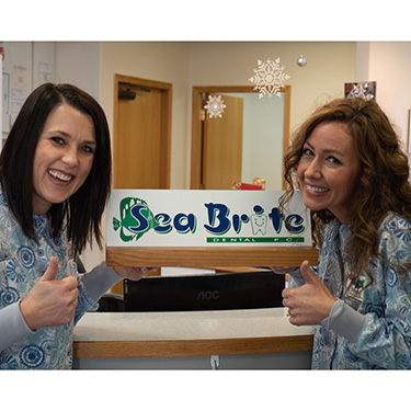 Misty and Sam holding Sea Brite Dental sign