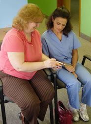 Chiropractic assistant helping patient fill out paperwork