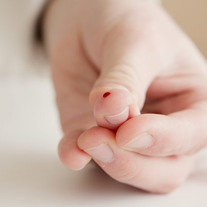 drop of blood on persons finger