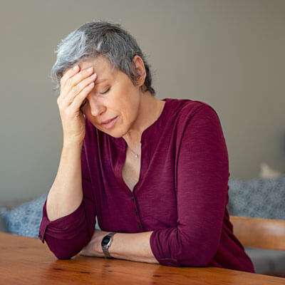 woman sitting at a table with a headache