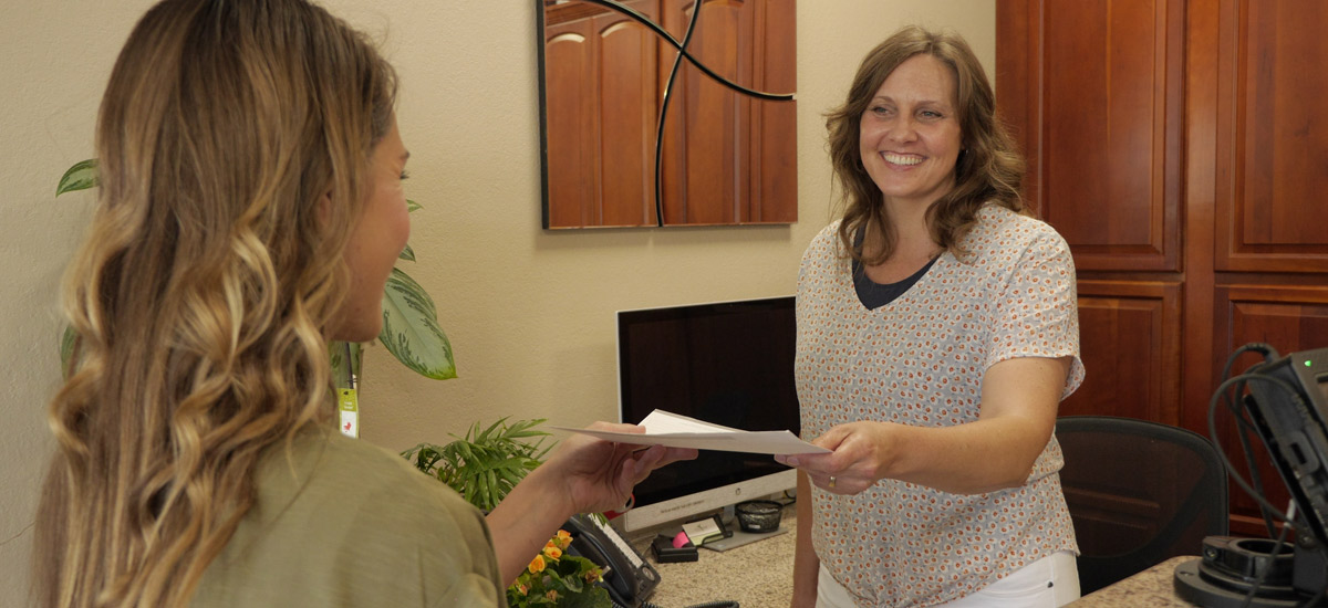 A new patient handing forms to the receptionist.