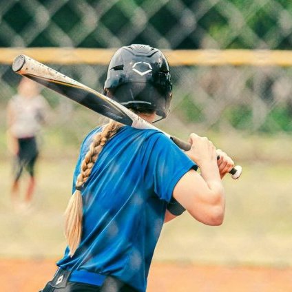 woman holding a baseball bat on top of a field