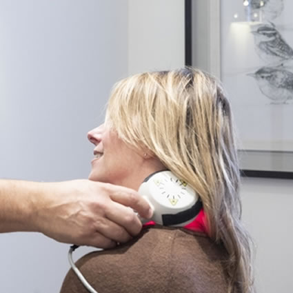 A woman receiving laser therapy on her neck.