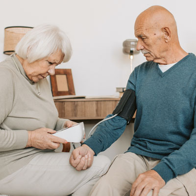 Woman checking man's blood pressure
