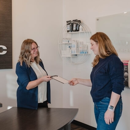 Pawlovich Chiropractic staff handing patient paperwork at our front desk