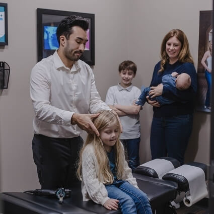 Dr Logan adjusting child with family nearby