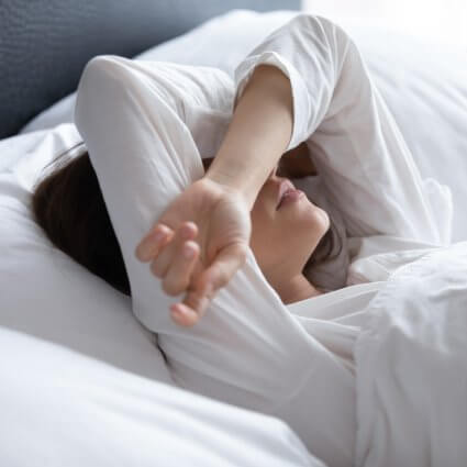 woman-lying-in-bed-arms-over-eyes-sq