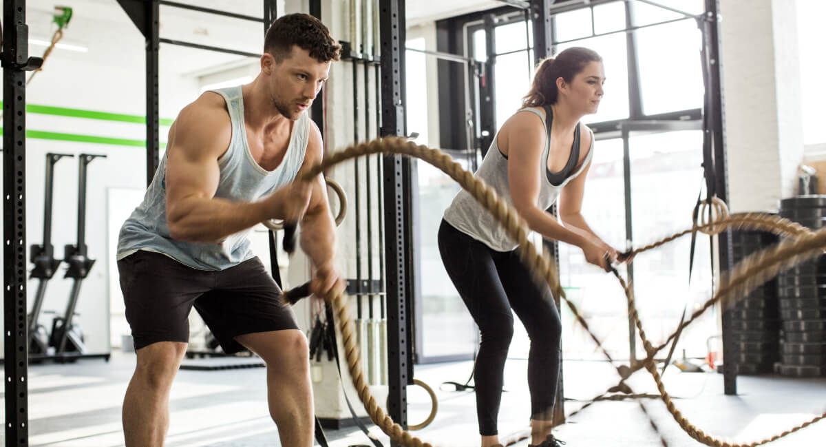 Man and woman training with ropes in gym