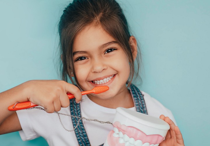 Child smiling while brushing her teeth
