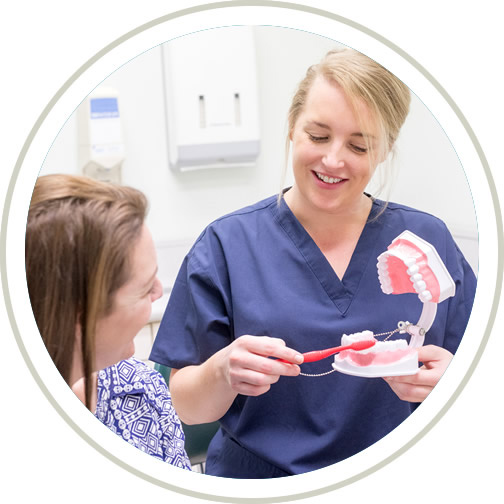 Dental hygienist demonstrating technique to patient