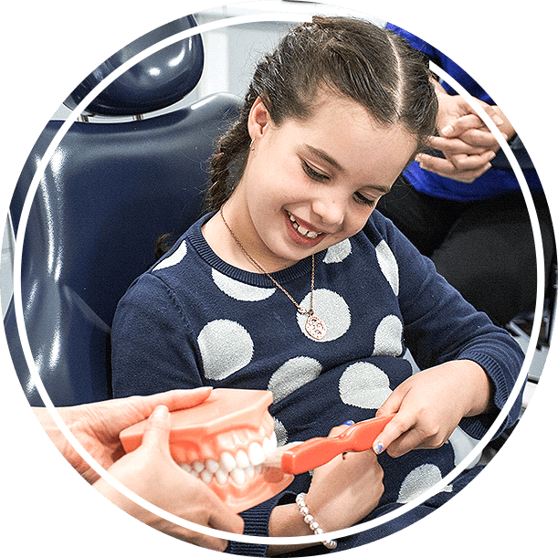 Young girl brushing model of teeth