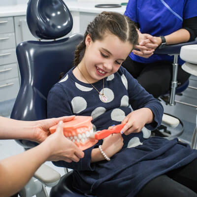 Little girl practicing brushing tooth model