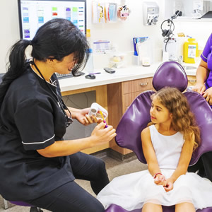 Female dentist demonstrating to young girl