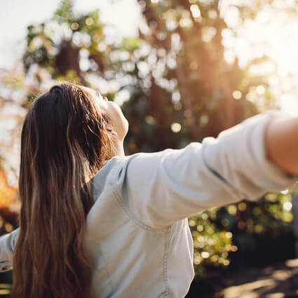 woman-looking-up-at-sun-with-arms-outstretched-sq