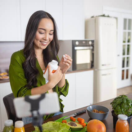 smiling-woman-green-top-looking-at-supplement-bottle-sq